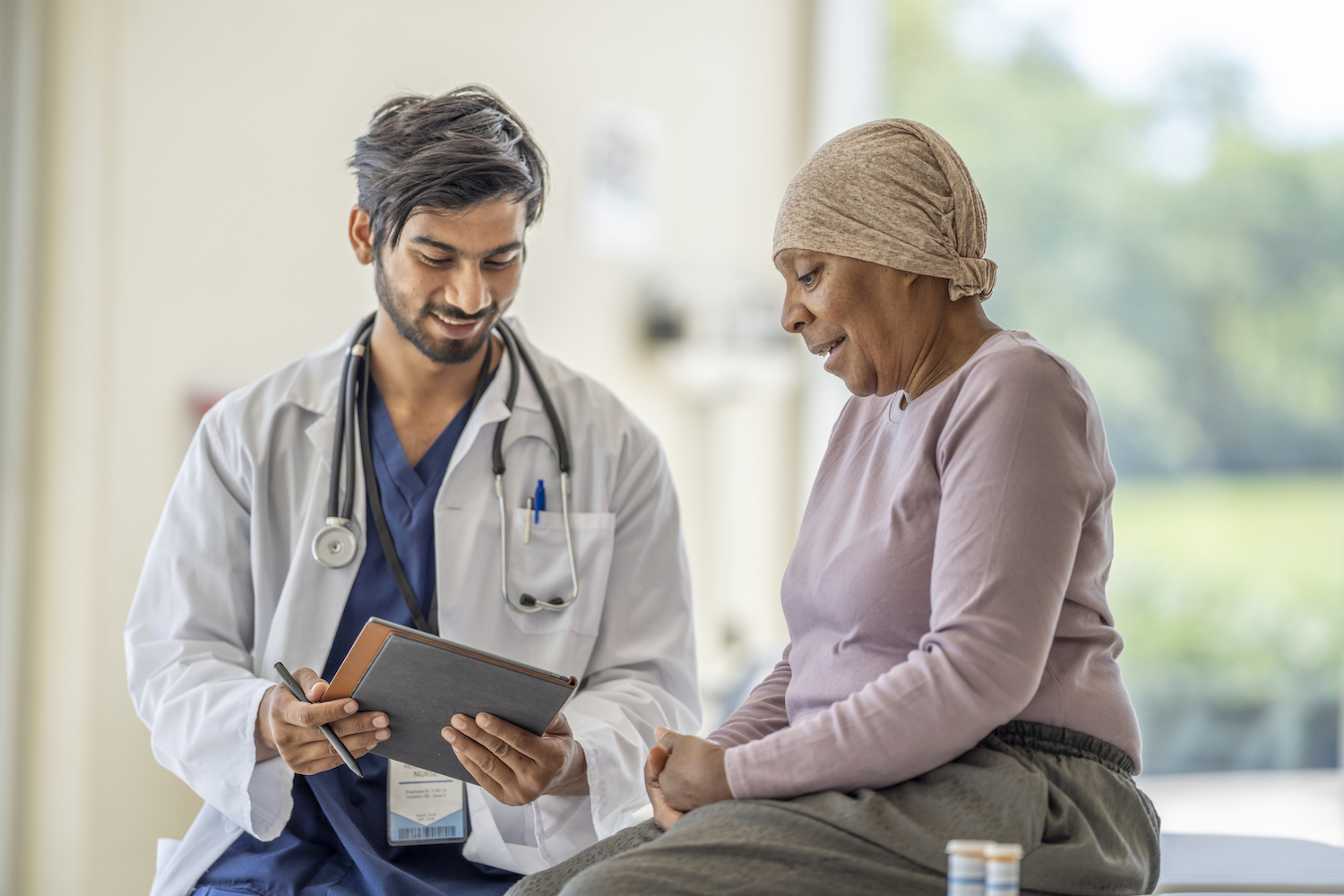 Doctor and patient in a clinical setting looking at a tablet computer together